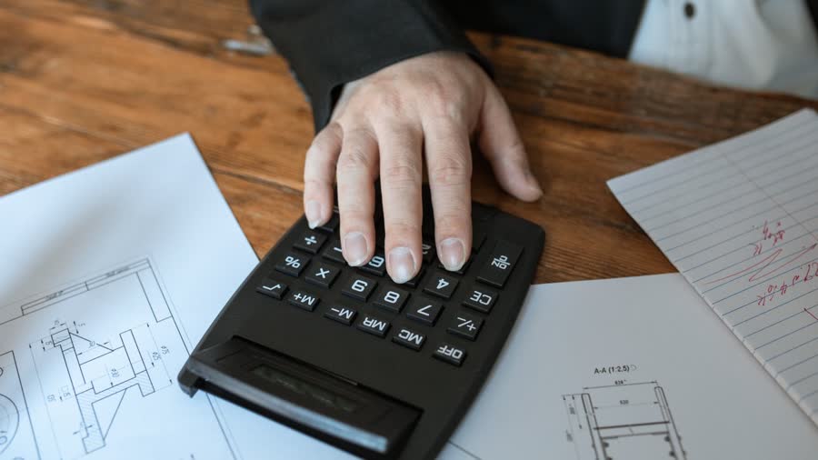 Calculatrice posée sur des plans, pour estimer une mensualité de prêt immobilier